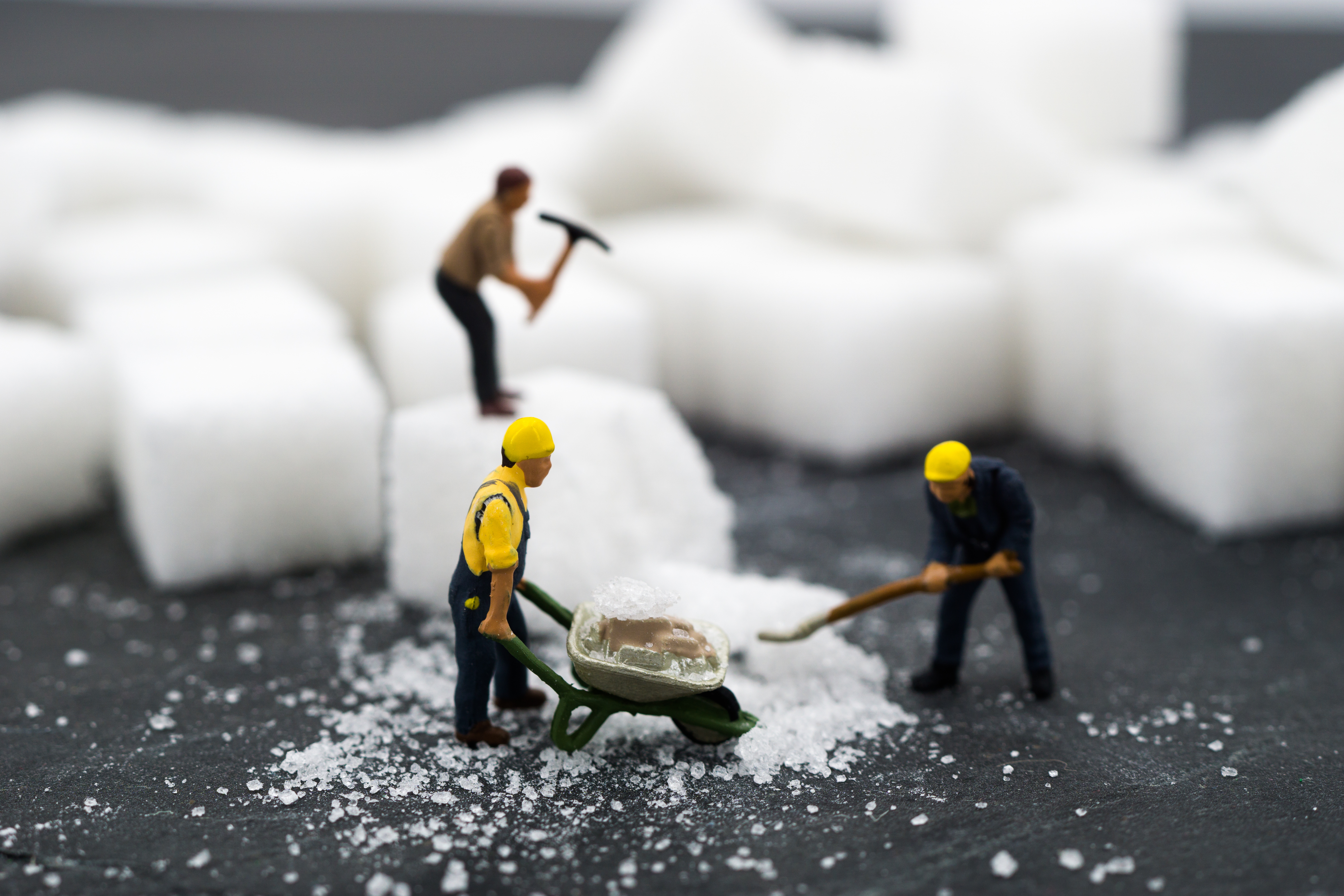 miniature workers with tools standing on sugar cubes