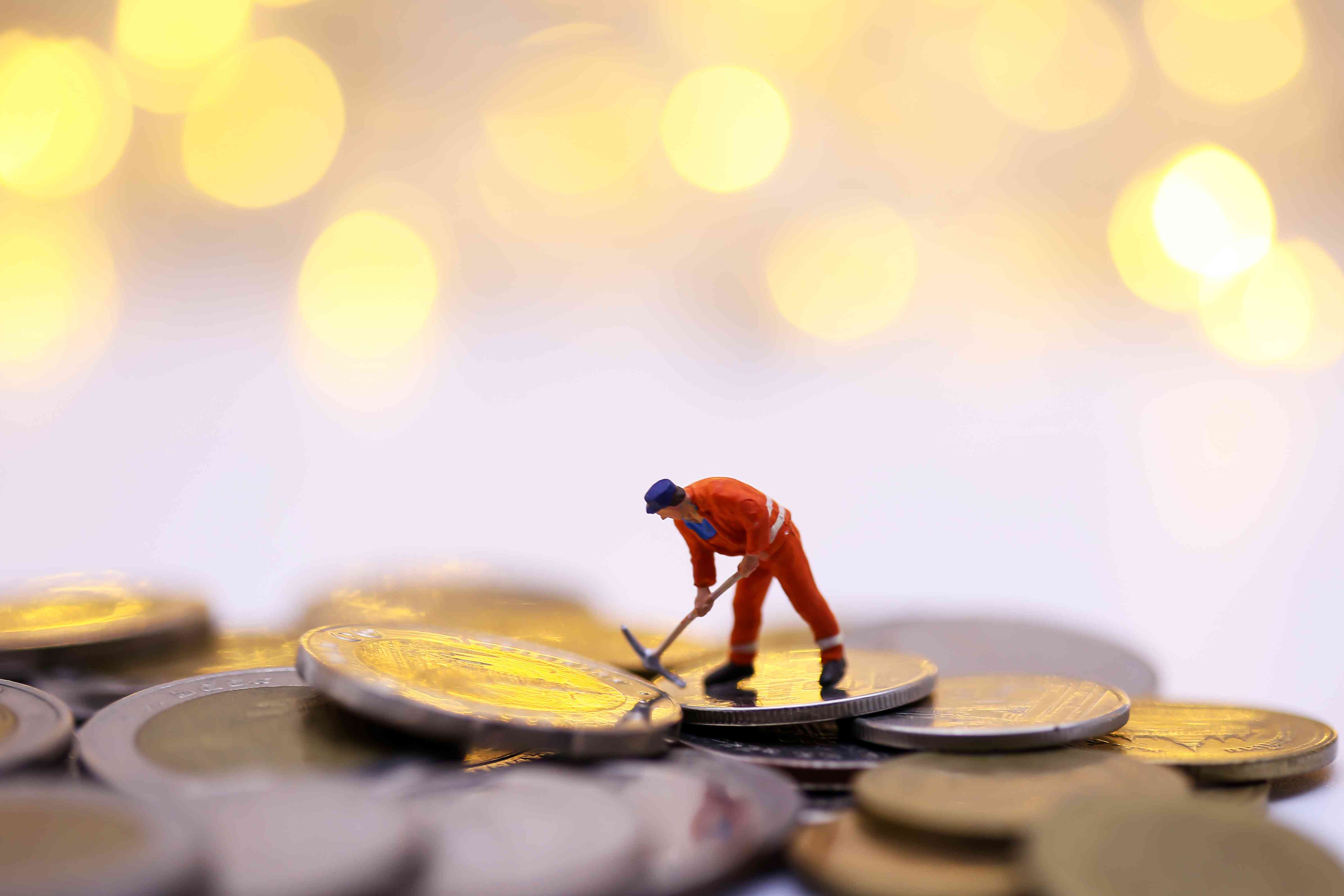 Small worker figurine standing on large coins